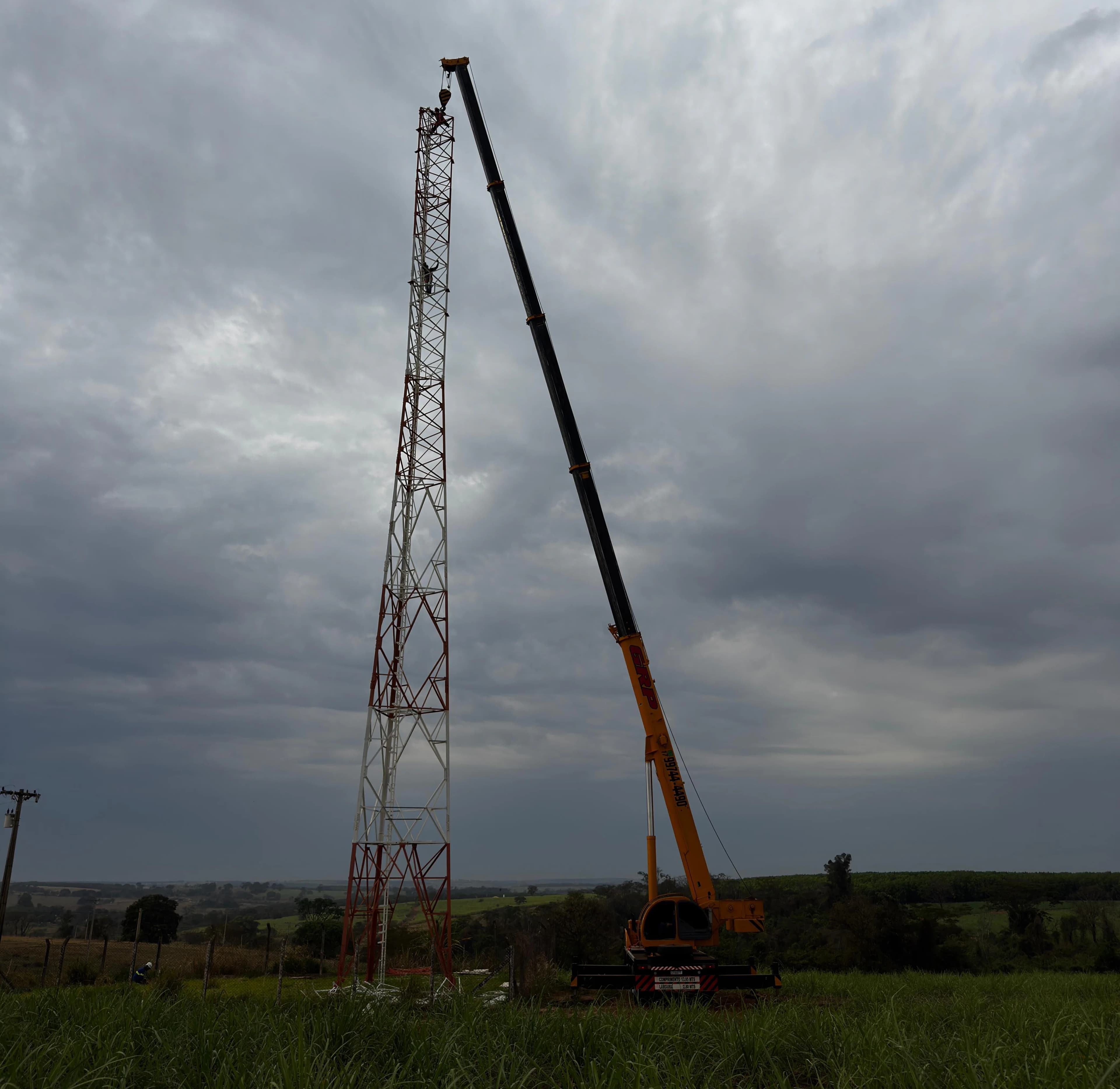 Guindaste mobilizado ao lado de torre de telecom em área rural